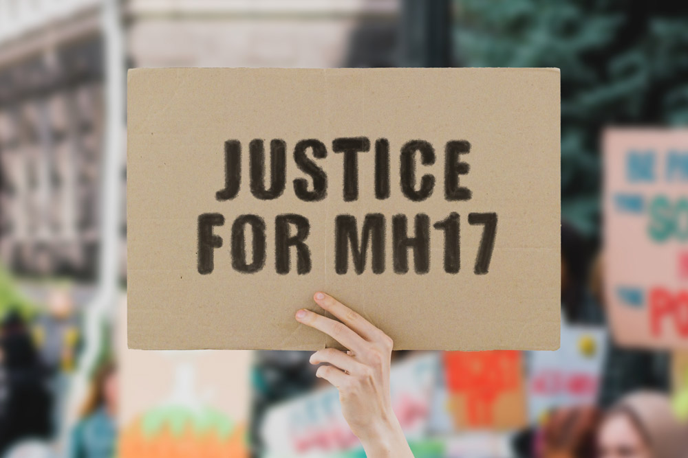 Hand holding cardboard sign stating 'Justice for MH17