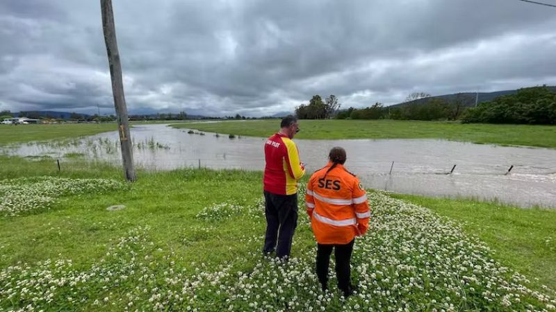 Two emergency services workers looking at flood waters in NSW. 