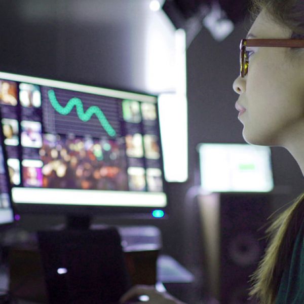 A woman's face is partially shown on the right hand side of the screen shw is waering glasses. She is looking at a computer screen that has images and a green squiggly line. University of Newcastle joins Uniseed venture fund to invest in future of Australian innovation.