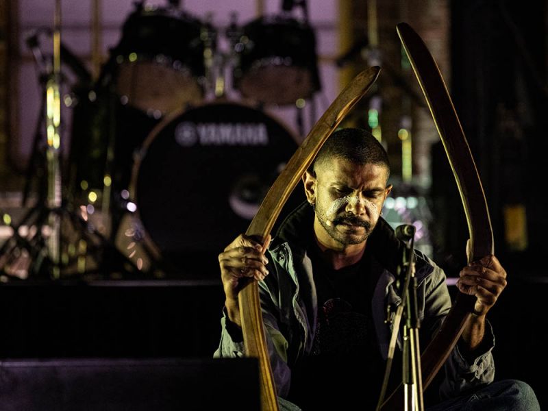 Male performer sitting on stage with musical instruments