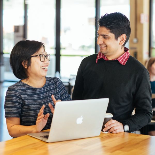 A woman and man stand behind a laptop smiling at each other. $438,000 funding to boost cleantech innovation in the Hunter