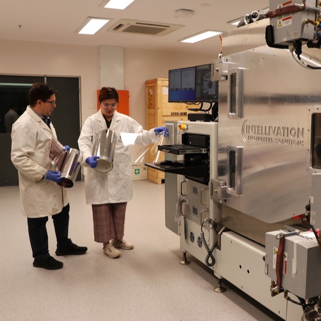 Two researchers working together and looking at a roll of printed solar