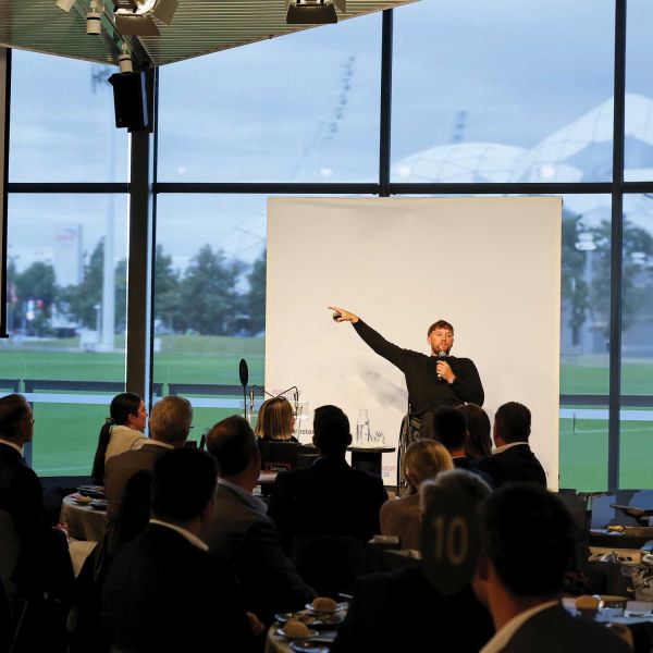 Man at a presentation pointing to his right with an audience in the foreground