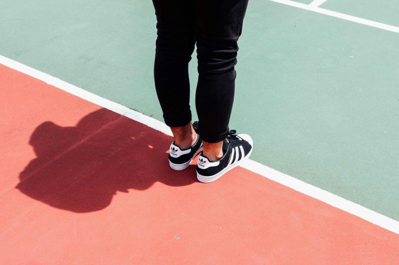Person wearing black adidas sneakers