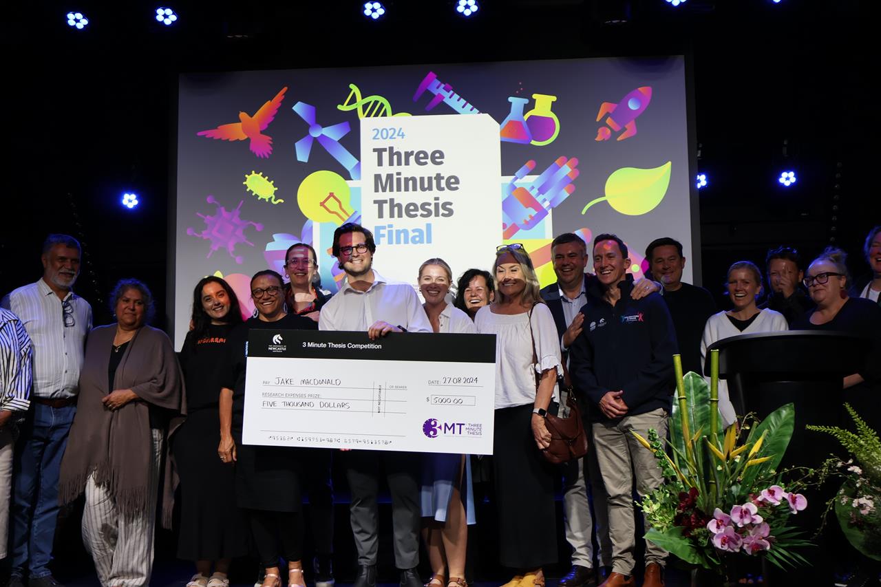 Jake MacDonald holding the first place cheque surrounded by his colleagues