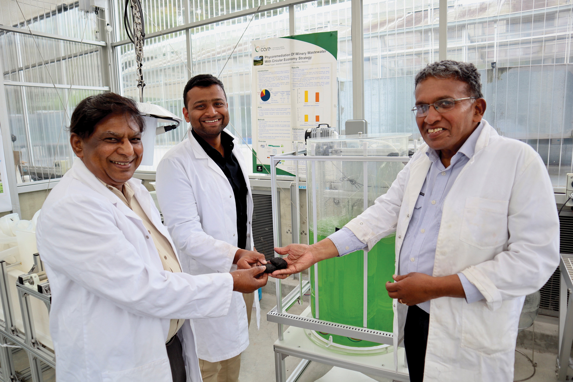 Three researchers in lab coats holding soil