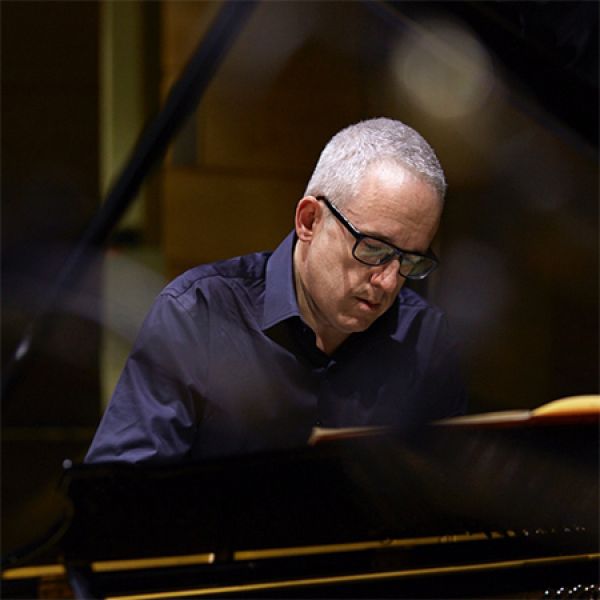 A person with short gray hair plays the piano.