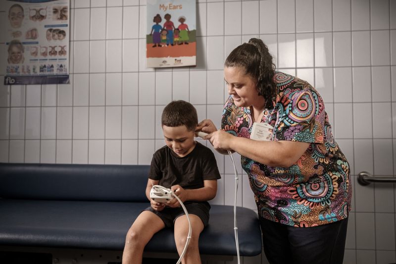 A young boy is having he's ears checked by a nurse