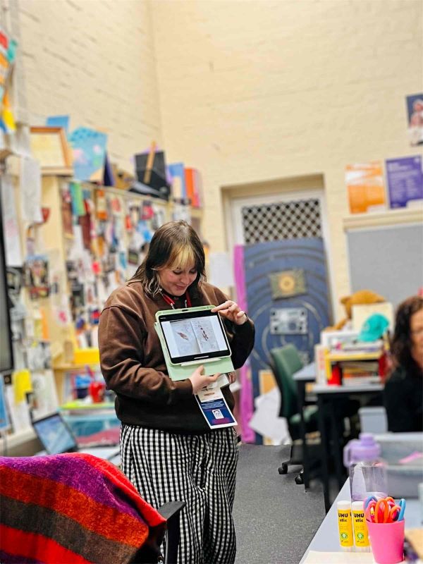 Young woman showing a high school class an A$ sheet with botanical prints made from ink pads