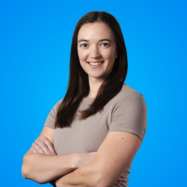 Woman smiling for camera in front of a blue background