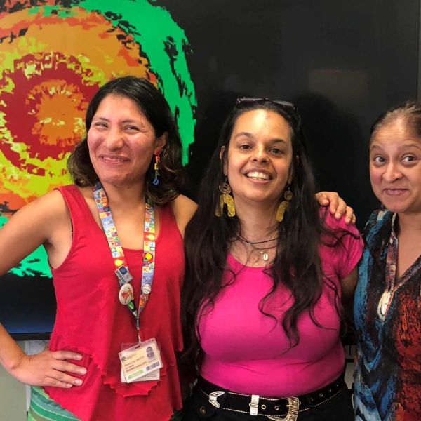 Three brown women with their arms around each other smiling. Feminisms from/of the Souths .