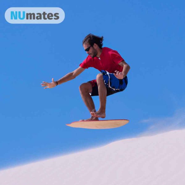 man on a sand board getting air over a sand dune
