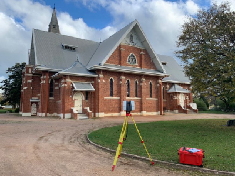 Image of surveying equipment in front of large, older building