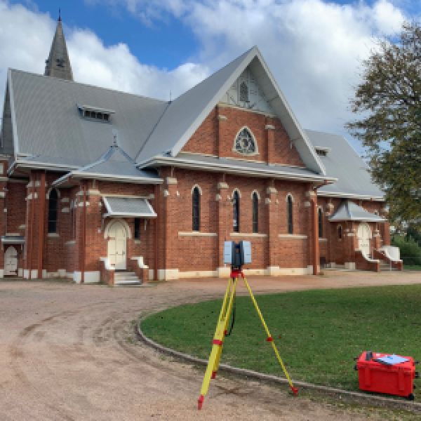 Image of surveying equipment in front of large, older building