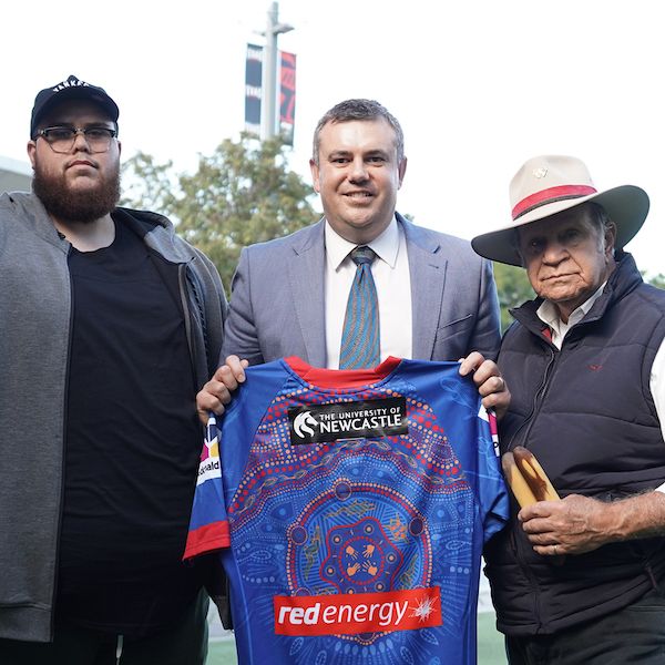 Nathan Towney holding Knights jersey. University of Newcastle joins back of jersey