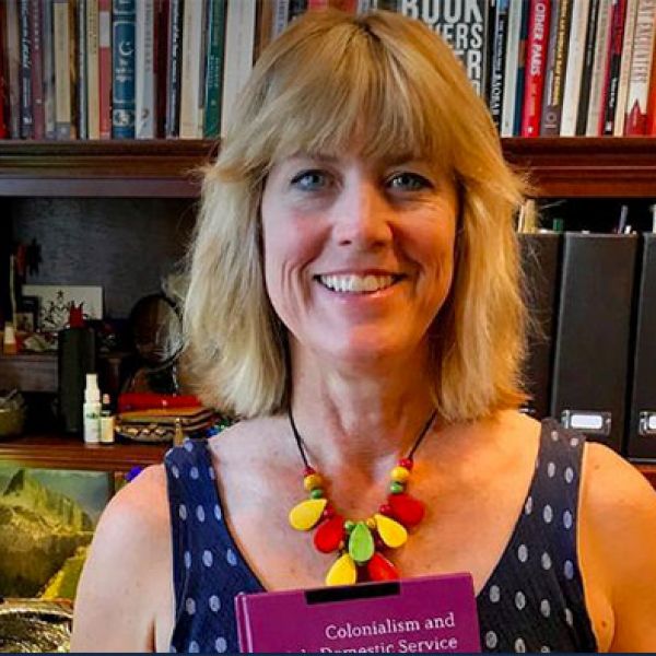Professor Victoria Haskins smiling and holding her book, 'Colonialism and Domestic Service.'. History of Domestic Service Podcast