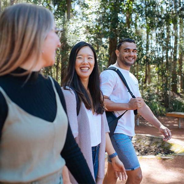 Three students walking on campus. Introducing our new Colleges