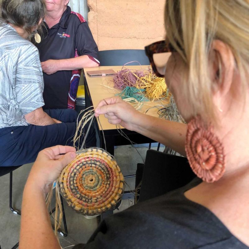 Close-up behind a woman wearing a woven earring doing some weaving