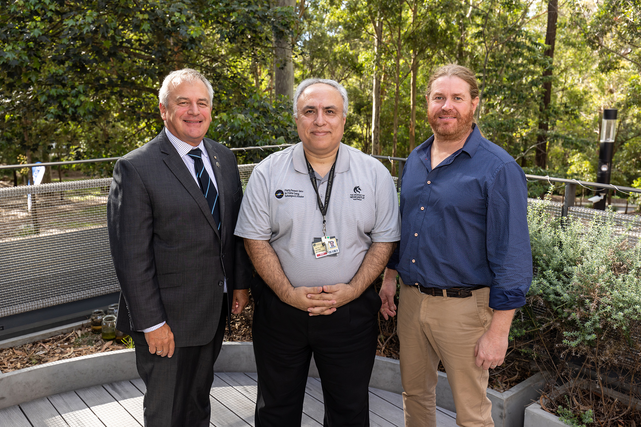 Three men stand looking at the camera
