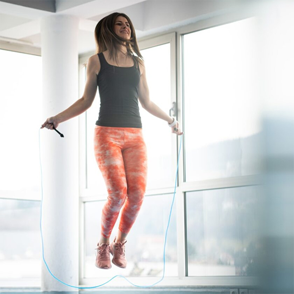 Woman exercising using a skipping rope in an indorr setting near windows