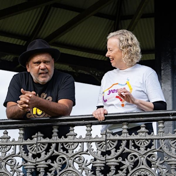 Two people wearing Yes t-shirts having a chat on a balcony 
