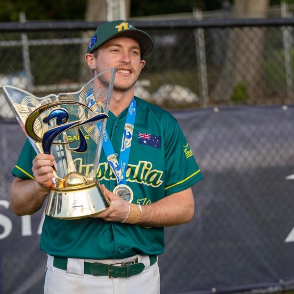Callum stands holding a trophy in softball uniform