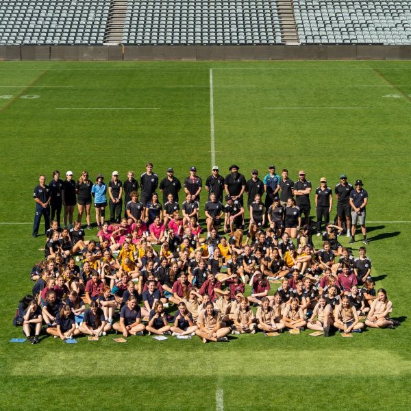 A group of female students and staff gather for a group photo on the field at Industree Stadium, Gosford. Hundreds of female students empowered to kick learning goals