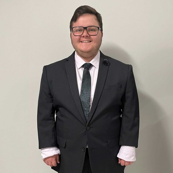 Young man in black suit smiling at camera. Shaping a positive future for LGBTQIA+ students