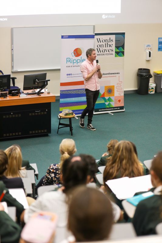 A man with a microphone addressing a room of students