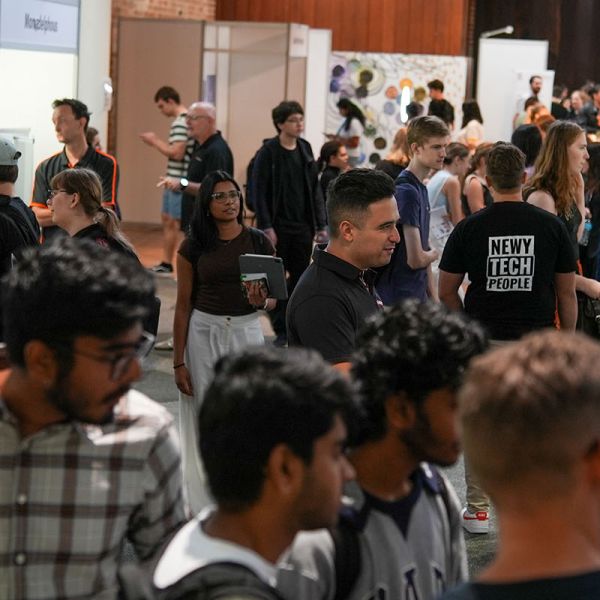 Crowd of people in a room looking at booths with employers and talking.