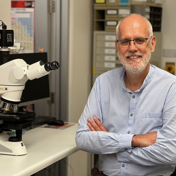 Picture of Professor Hubert Hondermarck, wearing a blue button up collared shirt with his arms crossed, in a laboratory.