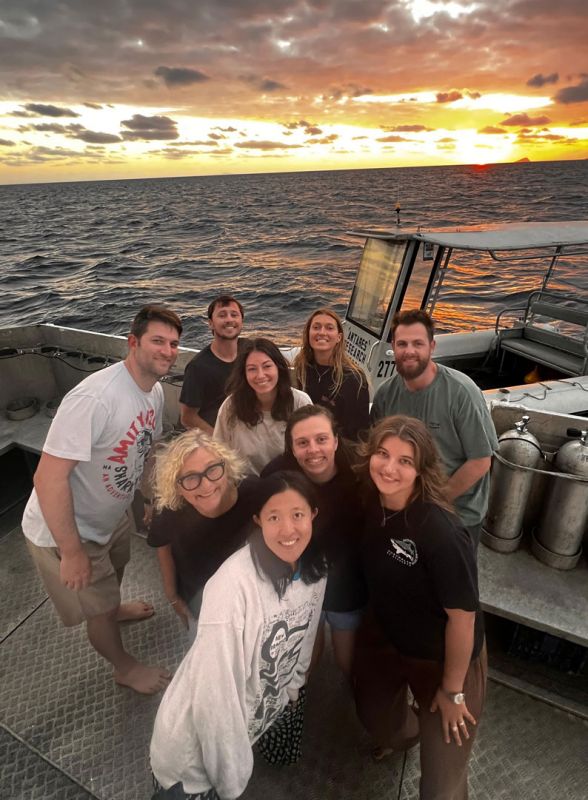 Sea cucumber research team smiling on a boat at sunset, while on a field expedition on the Great Barrier Reef.
