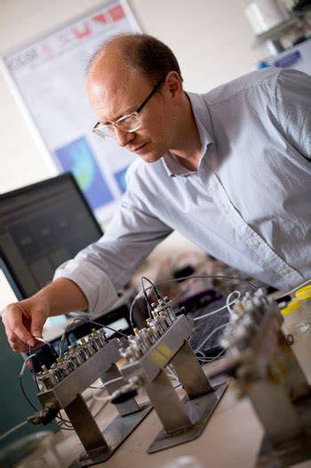 Man wearing glasses and a business shirt testing electronic devices in a lab