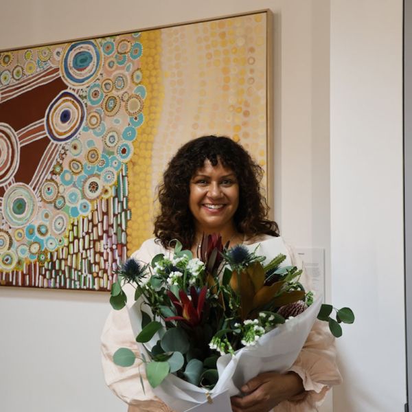 A woman standing in front of an indigenous artwork