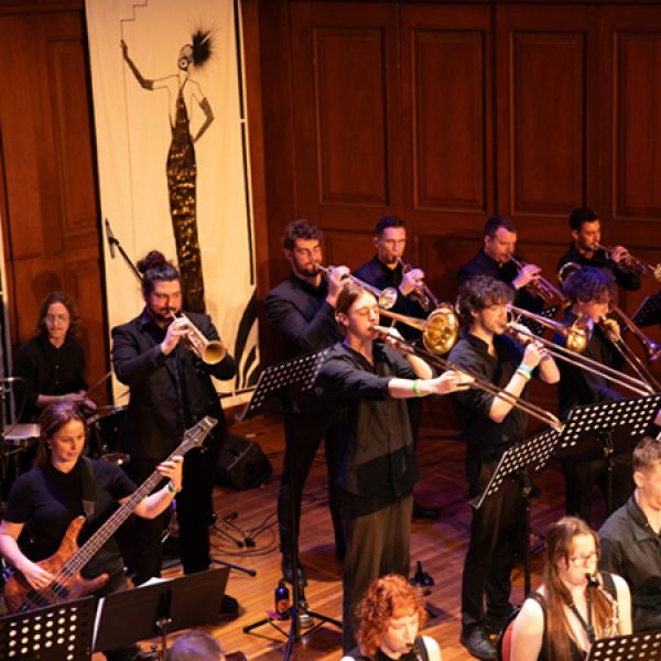 Musicians performing on stage with a variety of orchestral instruments.