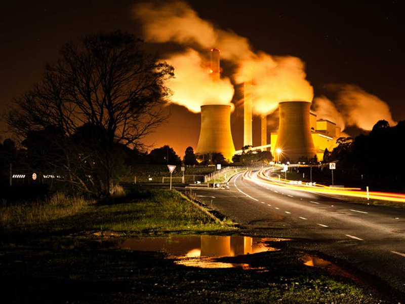 Night shot featuring factory chimneys billowing smoke