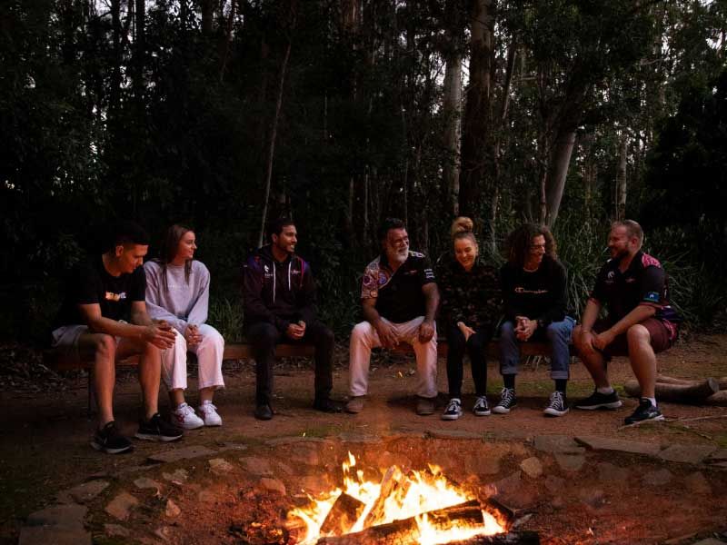 Dr Ray Kelly with students around a campfire