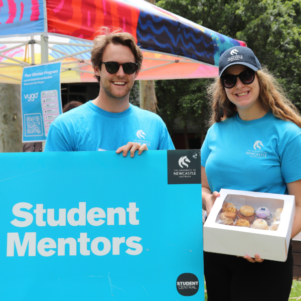 Two peer mentors with sign and cupcakes