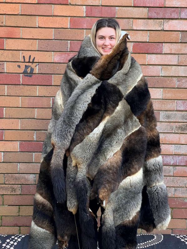 High school students standing in front of a brick wall wearing a possum skin cloak