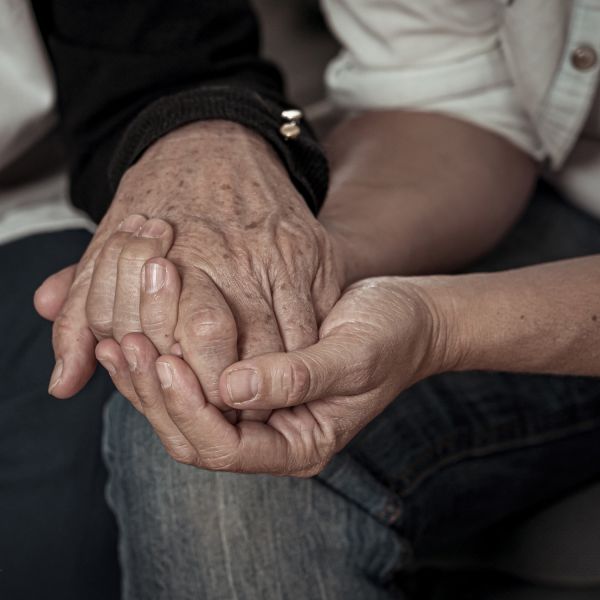 hands clasped of two people comforting each other