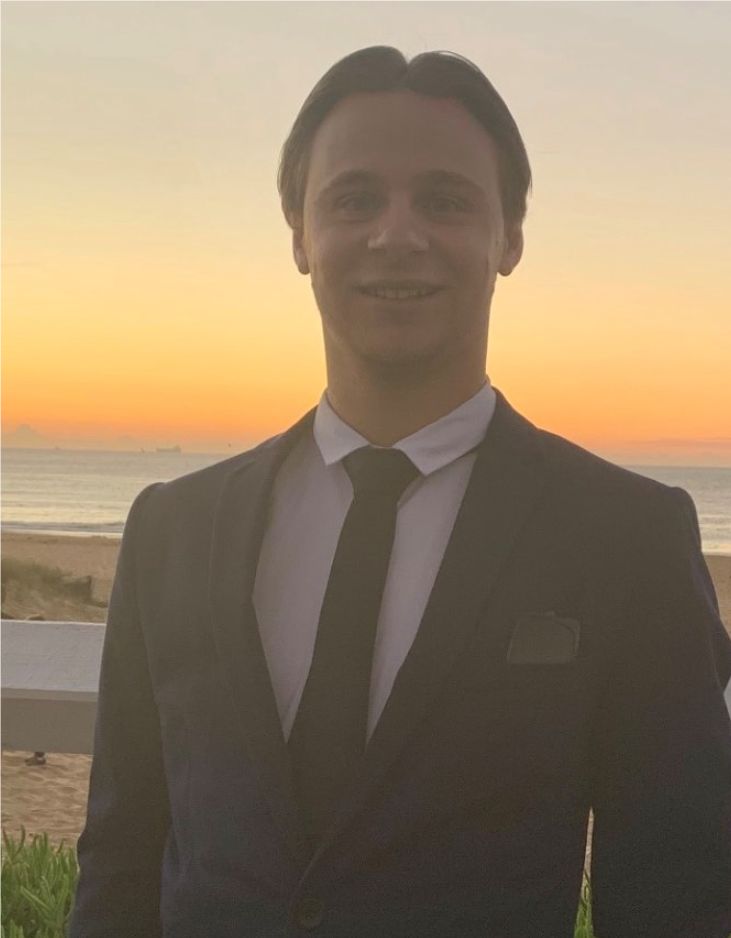 Nathan Hawkins smiling in front of a sunset at the beach