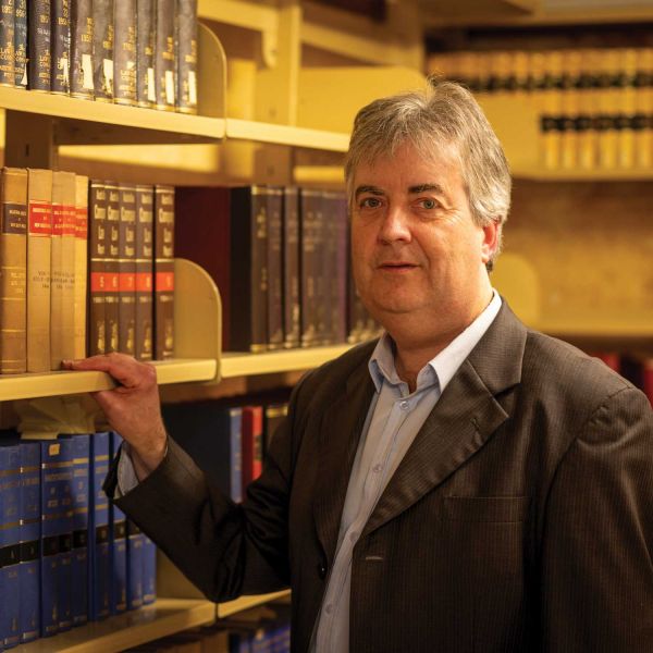 Man looking at the camera, surrounded by old text books