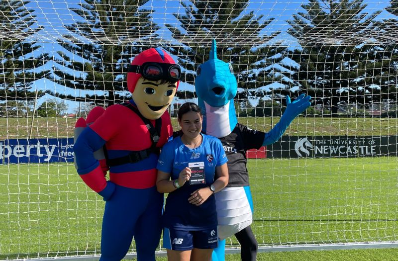 Two mascots with young girl presented with gift card