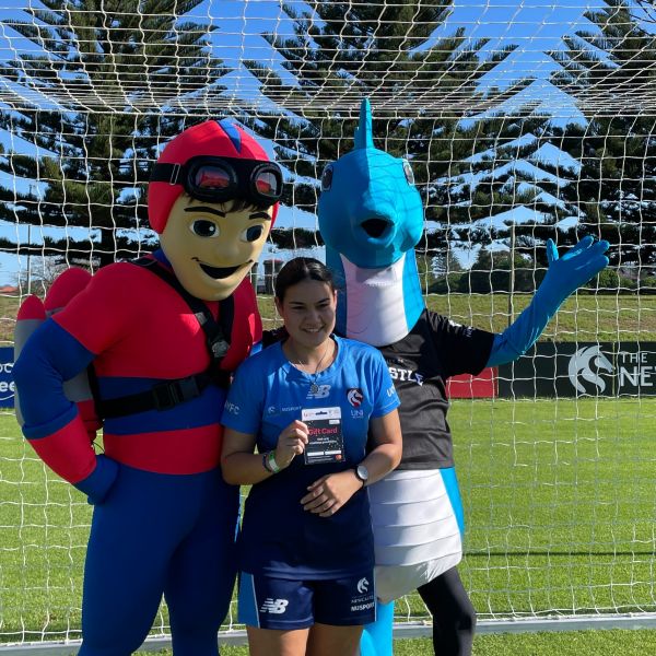 Two mascots with young girl presented with gift card