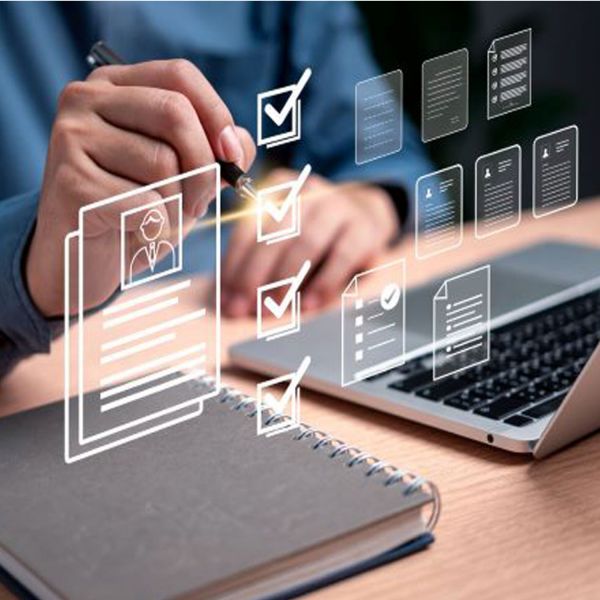 Image of man with pen checking tickbox with laptop and books