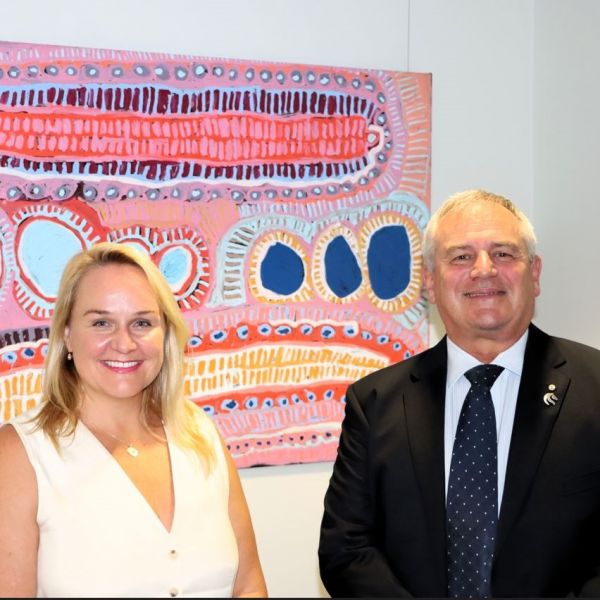 The Lord Mayor and the Vice-Chancellor stand together in front of an Indigenous artwork