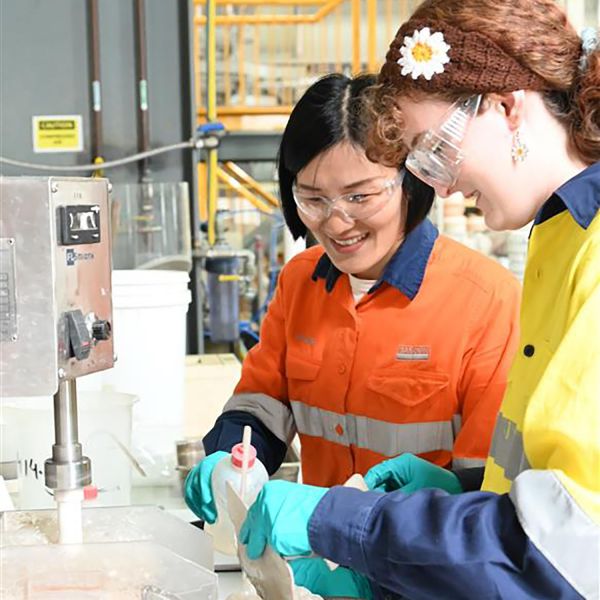 Two women in high vis clothing wearing saftey goggles work in a lab