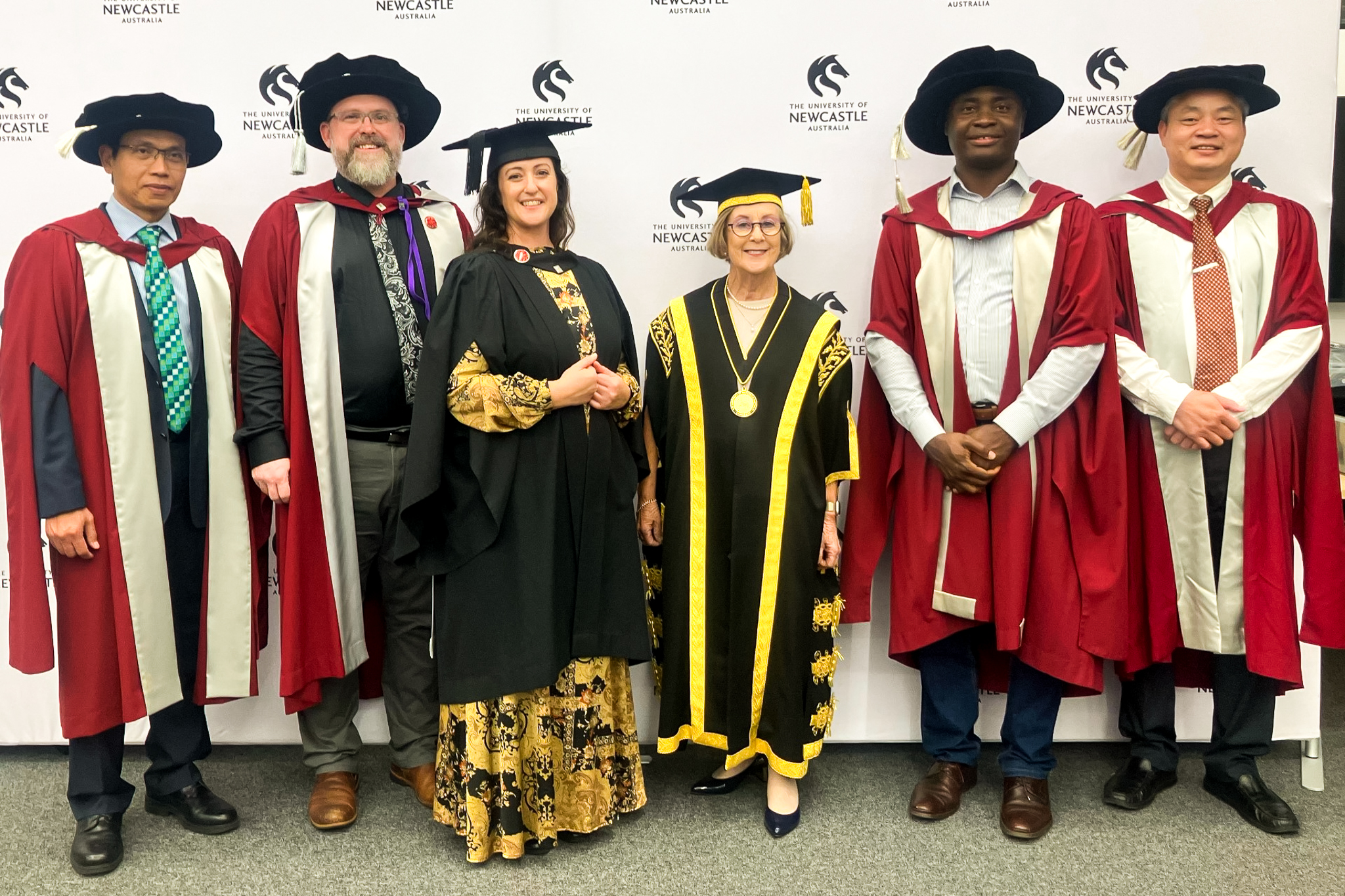 Graduate stands with Chancellor and four academics