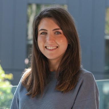 Woman with brown hair, wearing a blue sweater, smiling for the camera