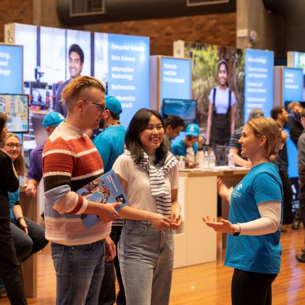 Two prospective students chat with a Student Ambassador at the Expo in the Great Hall at Newcastle Open Day. Thousands of people to get a taste of university life with robot soccer, Virtual Reality learning, mock court, and race cars at Newcastle Open Day